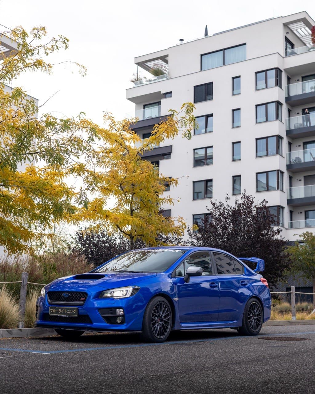 Blue Subaru WRX STI parked near an apartment building during autumn
